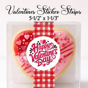 May include: A heart-shaped cookie with pink and red frosting, decorated with hearts and sprinkles, is packaged in a clear box. A red and white checkered ribbon wraps around the cookie, with a "Happy Valentine's Day" sticker. The sticker strips are 5-1/2" x 1-1/3".