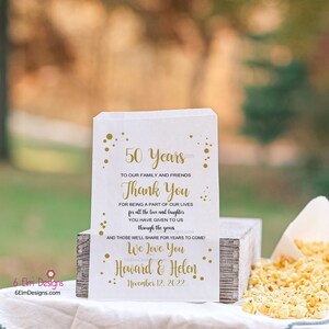 May include: White favor bag with gold text and confetti. The text reads "50 Years", "Thank You", "We Love You", "Howard & Helen", and "November 12, 2022".