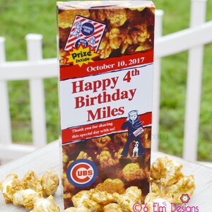 May include: A popcorn box with caramel popcorn and the text "Happy 4th Birthday Miles". The box has a red and white design with a sailor graphic and a "Prize Inside" logo. The Cubs logo is also visible.
