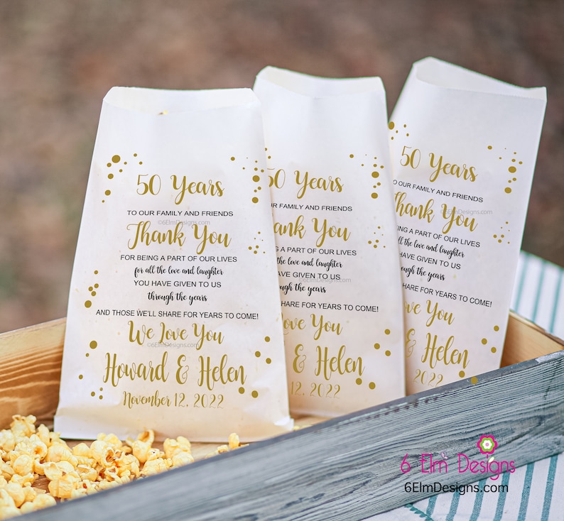May include: Three white paper bags with gold polka dots and text. The bags have a thank you message for being a part of our lives for all the love and laughter you have given to us through the years. The bags also say "We love you Howard & Helen" and "November 12, 2022".