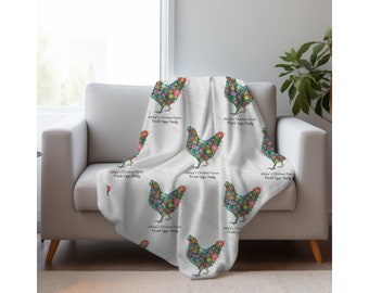 Può includere: Una coperta bianca con un motivo ripetuto di galline floreali, drappeggiata su una poltrona bianca. Il motivo della gallina è riempito di fiori colorati. Il testo "Abby's Chicken Farm Fresh Eggs Daily" è stampato sulla coperta.