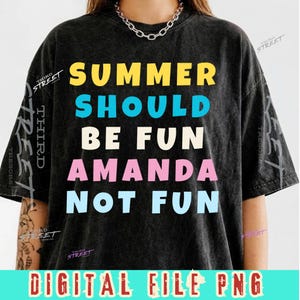 Peut inclure: Un t-shirt noir délavé à l'acide avec le texte "SUMMER SHOULD BE FUN AMANDA NOT FUN" en lettres capitales jaunes, cyan, crème, roses et bleu clair. Le t-shirt a un col rond et des manches courtes, avec un collier en argent visible.