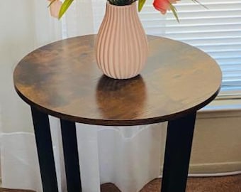 Mesa auxiliar redonda de estilo industrial, con estructura metálica y tablero de madera de ingeniería, ideal como mesita de noche o mesa auxiliar para sofá.