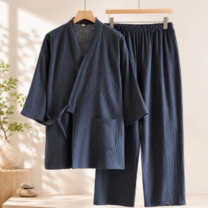 Peut inclure: Un ensemble de détente deux pièces bleu foncé composé d'une veste style cache-cœur avec des manches trois-quarts, une fermeture à nouer sur le côté et une poche plaquée, assorti d'un pantalon ample à taille élastique.