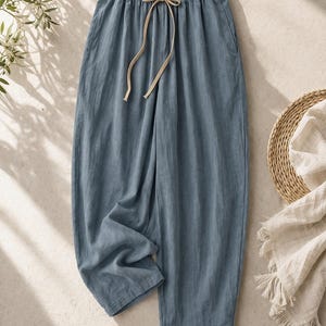 May include: A trio of cream-glazed ceramic mugs, each adorned with a hand-painted floral design in blue, green, and yellow hues. The mugs have a speckled finish and a classic, rounded form with a handle. Ideal for tea or coffee.