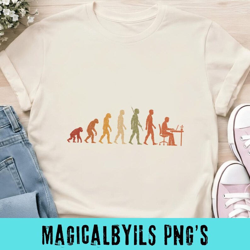 May include: A cream-colored short-sleeve t-shirt featuring a graphic print of human evolution in shades of orange and green. The design depicts the progression from a primate to a human sitting at a desk working on a laptop computer.