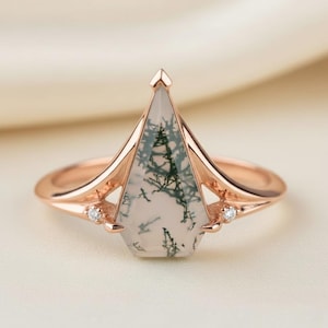 Puede incluir: Anillo de oro rosa con una gema geométrica única con inclusiones verdes y blancas, que recuerda a un paisaje. El anillo tiene una banda delicada y pequeños diamantes de acento. Una pieza de joyería elegante.