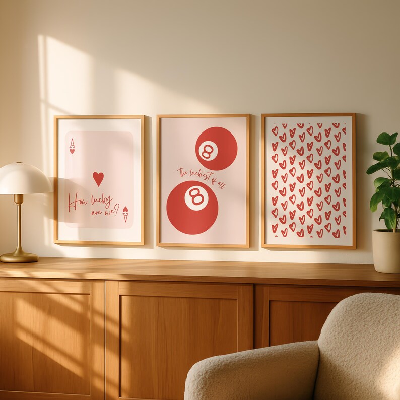 May include: Three framed art prints with a light wood finish. The prints feature a playing card design, a pair of red 8-balls, and a pattern of red hearts. Text on the prints reads "How lucky are we?" and "The luckiest of all."
