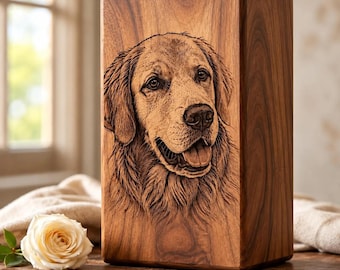 May include: A rectangular wooden urn featuring a detailed laser-engraved portrait of a Golden Retriever dog on the front panel. The wood displays a natural grain pattern in medium brown tones, and the dog is depicted with an open mouth.