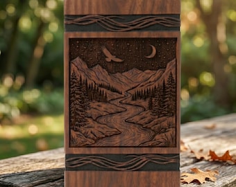 May include: A rectangular wooden box with a detailed landscape carving. The carving depicts a river winding through a mountain range, with an eagle and crescent moon in the sky. The box has decorative wave-like patterns.