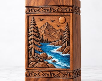 May include: A rectangular wooden box featuring a carved relief of a mountain landscape with pine trees and a blue river. The lid and base are decorated with a carved mountain and forest border. The wood has a natural brown grain finish.