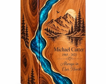 May include: A rectangular wooden cremation urn featuring a natural wood grain and a vertical, flowing inlay of bright blue resin. The front panel is laser-engraved with a mountain landscape, pine trees, a sun, and the text Michael Carter 1965-2023 Always in Our Hearts.