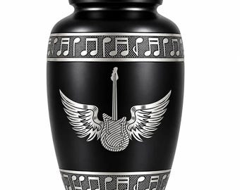 May include: A matte black cremation urn featuring a silver engraved electric guitar with wings in the center. The lid and the base are decorated with a silver band containing a repeating pattern of musical notes on a textured background.