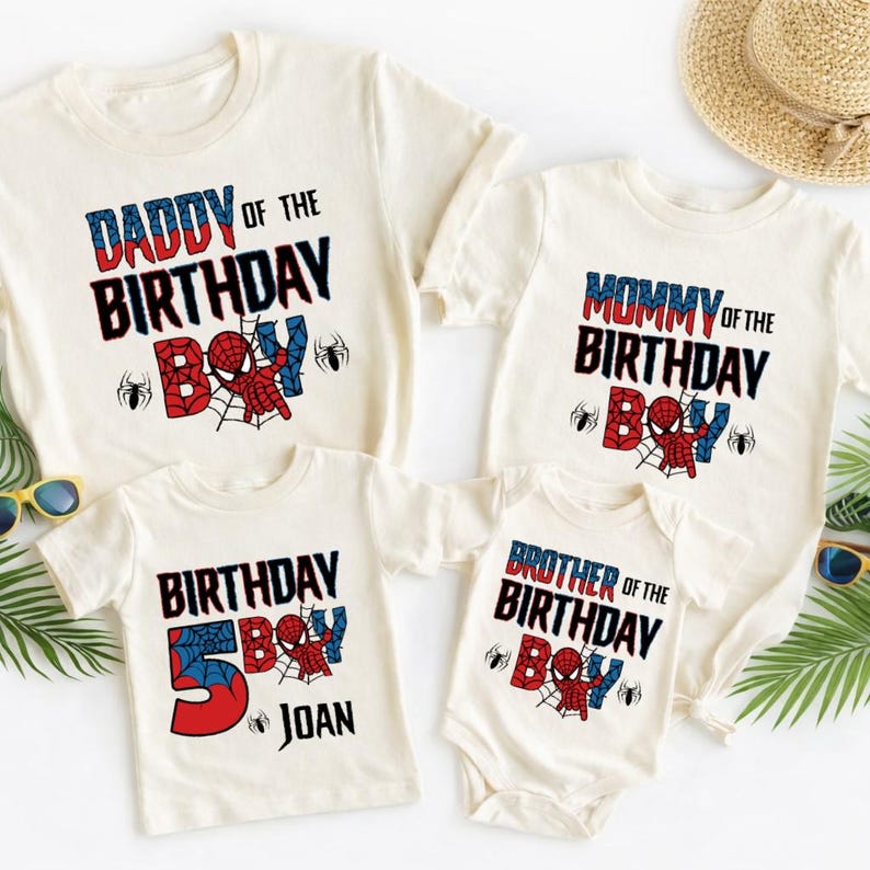 May include: Four off-white t-shirts and a onesie with superhero-themed birthday designs. The shirts read "Daddy of the Birthday Boy," "Mommy of the Birthday Boy," "Birthday Boy 5 Joan," and "Brother of the Birthday Boy."