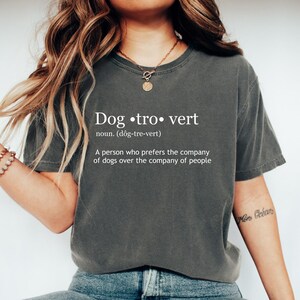 May include: Dark grey t-shirt with the word "Dogtrovert" in white, along with a definition. The definition reads: "A person who prefers the company of dogs over the company of people."