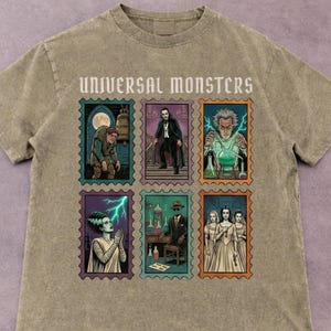 Könnte beinhalten: Ein sandfarbenes T-Shirt mit einer Grafik von sechs Briefmarken im Vintage-Stil mit Universal Monsters-Charakteren. Der Text "UNIVERSAL MONSTERS" ist oben aufgedruckt. Die Briefmarken zeigen Frankensteins Monster, Dracula und die Braut von Frankenstein.