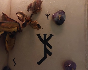 May include: An open book with blurred text, adorned with dried flowers and runes. Three purple gemstones with gold symbols are scattered around the page. A black rune symbol is prominently displayed.