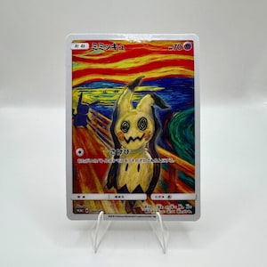 May include: A Pok&eacute;mon trading card featuring Mimikyu in a parody of The Scream painting. The card has Japanese text and a yellow, black, and white colour scheme. The card is displayed on a clear acrylic stand.