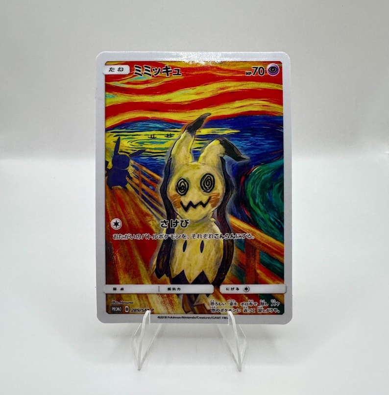 May include: A Pok&eacute;mon trading card featuring Mimikyu in a parody of The Scream painting. The card has Japanese text and a yellow, black, and white colour scheme. The card is displayed on a clear acrylic stand.