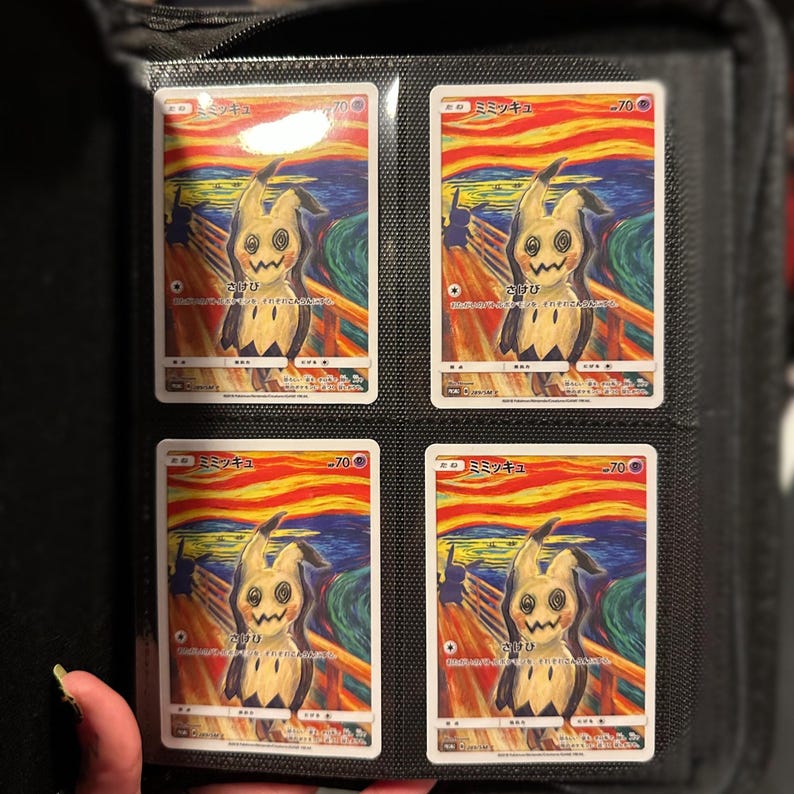 May include: Four trading cards featuring a Mimikyu character in a parody of Edvard Munch's "The Scream" painting. The cards are in a black binder, each card displaying the character against a swirling orange, yellow, and blue background. Japanese text is visible on the cards.
