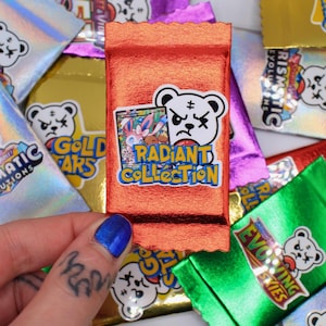 May include: An orange foil pack with a white bear sticker that reads "Radiant Collection" and a colorful card inside. Other packs with the same bear logo and text like "Prismatic Evolutions" and "Evolving Skies" are in the background.