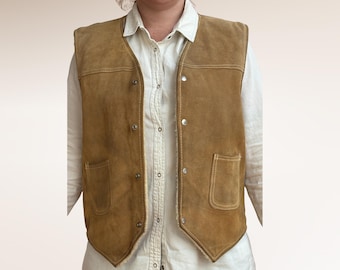 May include: A tan suede vest with a button-up front, two front pockets, and a cream-colored lining. The vest is worn over a white button-down shirt. The vest has a classic, vintage style.