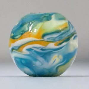 May include: A round, colorful bead with a marbled design. The bead features swirls of blue, yellow, white, and orange. The bead is a decorative element, possibly for jewelry or crafts.