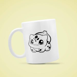 May include: White ceramic mug featuring a black and white cartoon illustration of a Bulbasaur. The Bulbasaur design includes large eyes and black spots. The mug has a curved handle and is set against a yellow background.