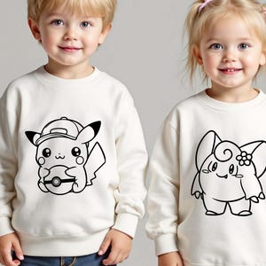 May include: Two off-white sweatshirts featuring black line art of Pok&eacute;mon characters. One sweatshirt has Pikachu wearing a cap and holding a Pok&eacute; Ball. The other has a Clefairy design. Both are long-sleeved.