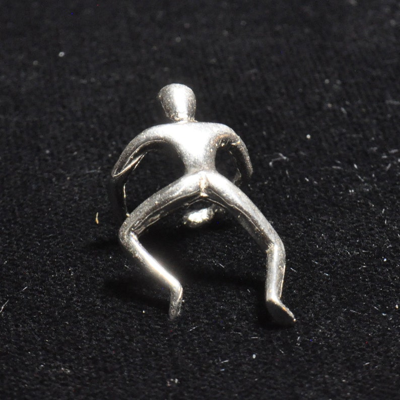 May include: A silver-toned metal sculpture of a person in a crouching pose.