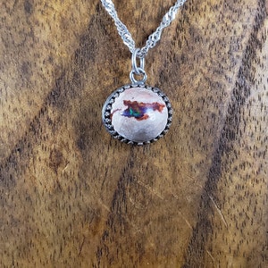 May include: A silver chain necklace with a round opal pendant set in a silver bezel. The opal has a white base with iridescent green, blue, and red flashes.