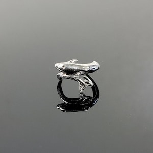 May include: Silver ring with a stylized fish design. The fish is curled around the ring band.