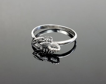 May include: A silver ring with a scorpion design. The scorpion is detailed and has a textured finish.