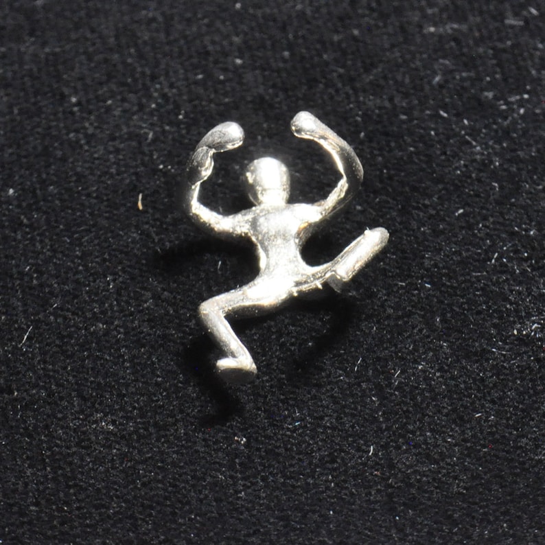 May include: A silver figurine of a person in a jumping pose with arms raised above their head.