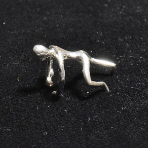 May include: Silver abstract sculpture of a person in a bent-over pose. The sculpture is made of smooth, shiny metal and has a modern, minimalist design.