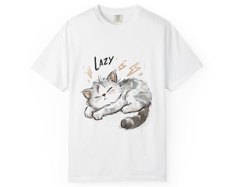 Può includere: T-shirt bianca con un'illustrazione a cartoni animati di un gatto grigio e bianco che dorme e la parola "LAZY". Il gatto ha gli occhi chiusi e una postura rilassata. Grafiche di fulmini dorati sono sulla maglietta.