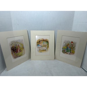Könnte beinhalten: Drei gerahmte Drucke mit Illustrationen von Beatrix Potter. Der linke Druck zeigt einen Hasen im Garten, der mittlere Druck einen Hasen beim Backen in einer Küche und der rechte Druck einen Hasen mit einer Schaufel und einem Vogel.