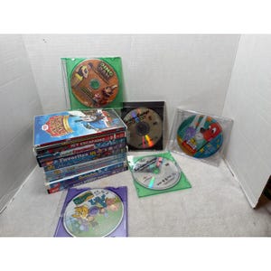Może przedstawiać: Kolekcja płyt DVD dla dzieci zawierająca stos pudełek z tytułami takimi jak Thomas & Friends Holiday Express, Icy Escapades i Blue's Biggest Stories, oraz pojedyncze płyty dla Dino Dan, Curious George i Clifford the Big Red Dog.