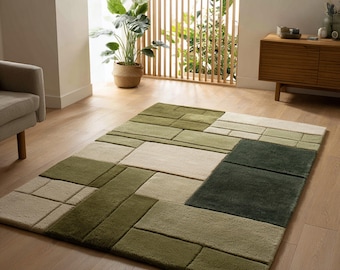 May include: A rectangular area rug with a geometric pattern in shades of green and beige. The rug features a patchwork design with various rectangular shapes, creating a modern and textured look. The rug is placed on a wooden floor.