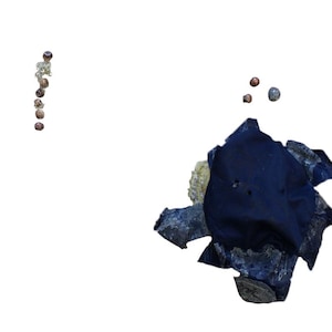 May include: An abstract composition featuring several small, dark, spherical objects arranged in vertical lines. A dark blue, irregularly shaped fabric piece is surrounded by light-colored, textured stones and a few scattered spheres.