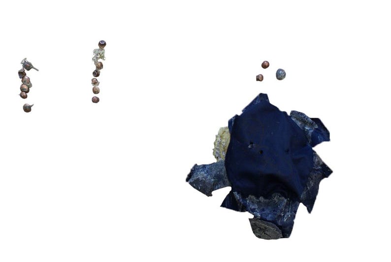 May include: An abstract composition featuring several small, dark, spherical objects arranged in vertical lines. A dark blue, irregularly shaped fabric piece is surrounded by light-colored, textured stones and a few scattered spheres.