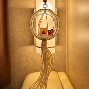 May include: A decorative hanging light fixture with a glass orb and a tassel. The fixture has a cylindrical light source and is adorned with a small wooden chair and heart-shaped decor. The text "Coastal Beach Home" is at the bottom.