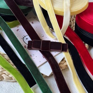 Könnte beinhalten: Eine Sammlung von Samtbändern in verschiedenen Farben, darunter Dunkelbraun, Hellgelb, Waldgrün, Schwarz und Rot. Eine dunkelbraune Samtschleife ist auf einer weißen Karte mit einer kleinen Hello Kitty-Grafik und Text zentriert.