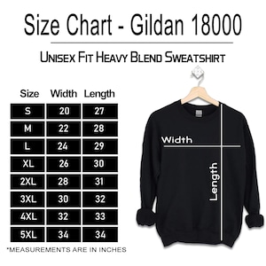 May include: A black Gildan 18000 unisex heavy blend sweatshirt on a hanger next to a size chart. The chart lists sizes S through 5XL with corresponding width and length measurements in inches. The sweatshirt features white lines indicating width and length.