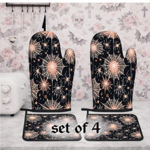 May include: A set of 4 black oven mitts and pot holders with a spiderweb and spider design in copper color. The text "set of 4" is visible on the pot holders. The kitchen accessories are designed with a Halloween theme.