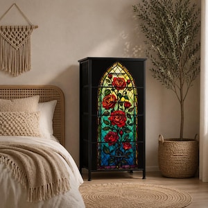May include: Black cabinet with a stained glass design featuring red roses. The cabinet has a rectangular shape with a decorative arched panel. The roses are set against a backdrop of yellow, green, and blue hues, resembling a church window.