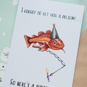 May include: A humorous birthday card featuring a cartoon codfish wearing a party hat and holding a fishing rod with a lit candle. The card reads "I forgot to get you a present... So here's a birthday cod."