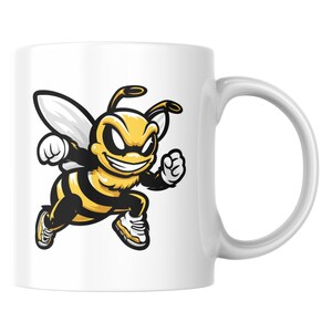 May include: White ceramic mug with a cartoon bee design. The bee is yellow and black, running with clenched fists and wearing trainers. The mug has a curved handle. The design is a bold, graphic illustration.