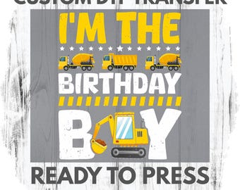 May include: A gray DTF transfer design with the text "I'M THE BIRTHDAY BOY" in yellow. The design includes illustrations of construction vehicles: cement mixers, a dump truck, and an excavator. The text "READY TO PRESS CUSTOMIZATION OPTION" is also included.