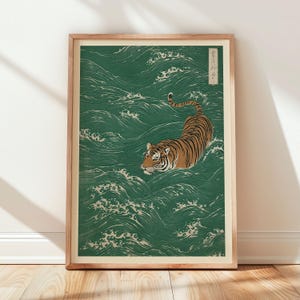 May include: A framed art print featuring a tiger swimming in a sea of green waves. The tiger has orange and black stripes. The artwork is in a traditional Japanese style, with a wooden frame.